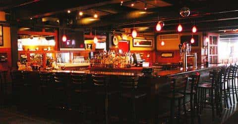 a view of the bar area with bar stools lining the sides and a large liquor collection