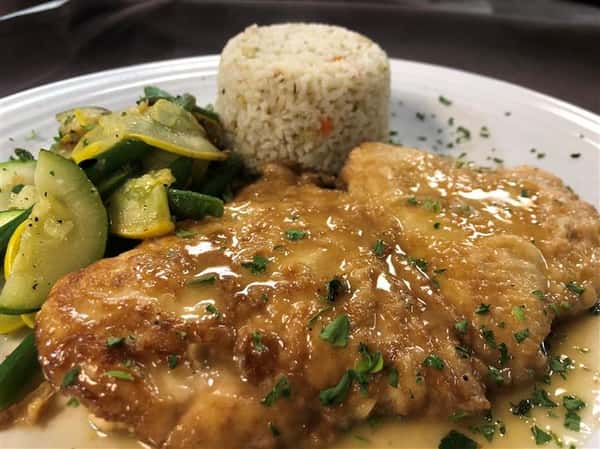 breaded chicken with orange sauce on top with a side of white rice and zucchini and string beans