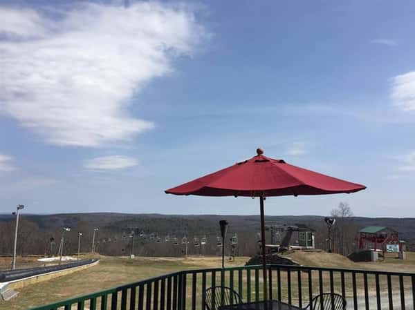outdoor seating area displaying a table with two chairs and a red umbrella