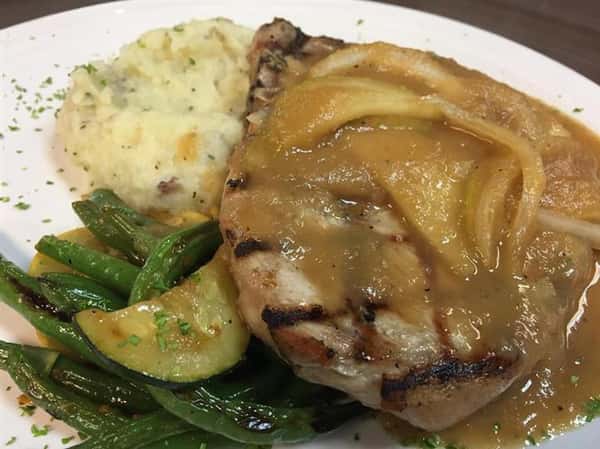 grilled chicken with a gravy sauce and a side of string beans and mashed potaotoes