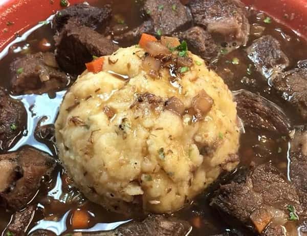 stew meat in a pool of gravy with a scoop of mashed potato