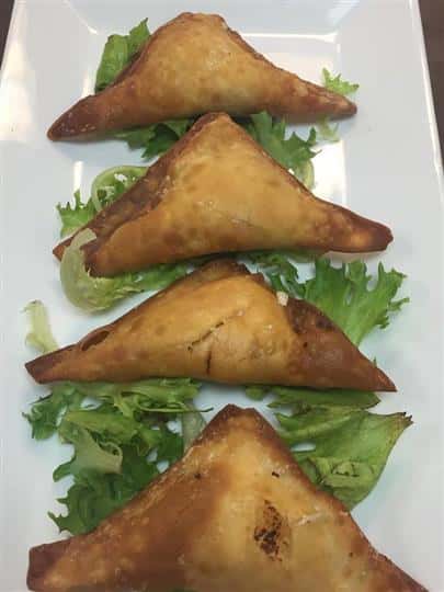 four empanadas on a plate in a bed of lettuce