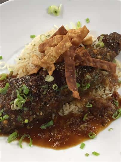 meat on a bed of white rice, gravy and crunchy noodles