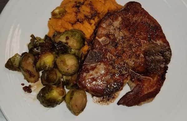 a steak with a side of halved brussel sprouts and yams