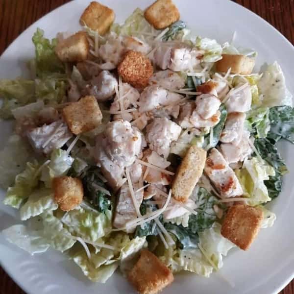 chicken caesar salad topped with cheese and croutons