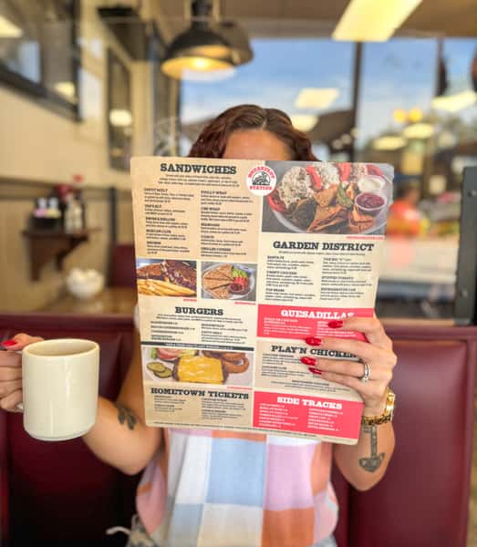 guest looking at a menu holding a coffee cup