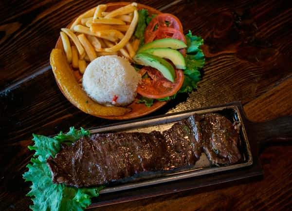 grilled steak with rice, fresh tomatoes and avocados, and fries