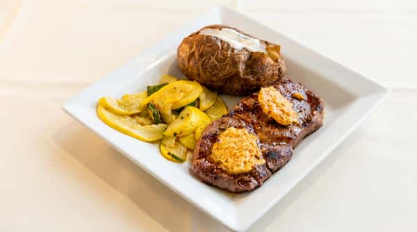 Grilled steak with herb butter, baked potato, and sautéed squash served at Serafini, an Italian fusion restaurant in Frankfort, Kentucky.