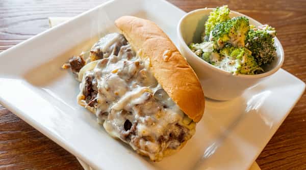 Philly cheesesteak sandwich with melted provolone and seasoned beef, served with a fresh side at Serafini in Frankfort, Kentucky.