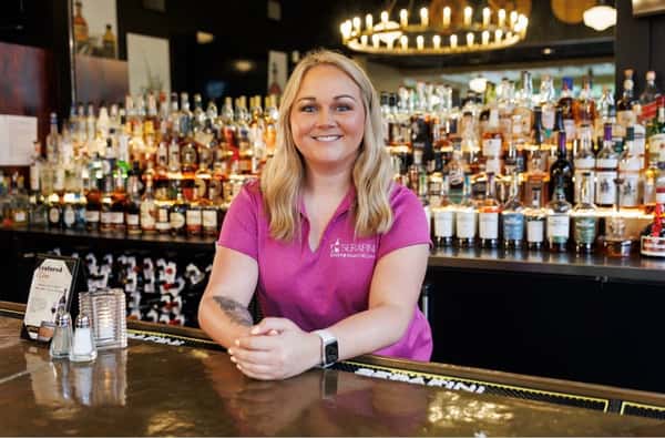 Friendly bartender behind the bar at Serafini, welcoming guests to the Italian fusion restaurant in historic downtown Frankfort, Kentucky.
