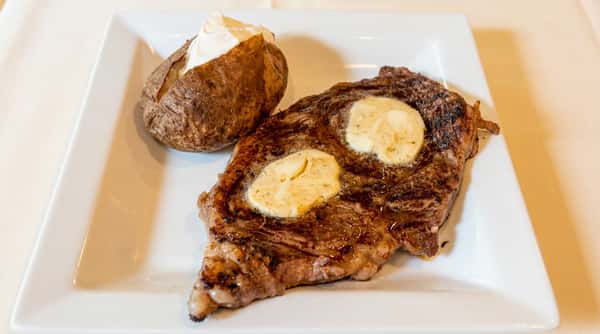 Prime ribeye steak finished with herb butter and served with a baked potato at Serafini, an Italian fusion restaurant in Frankfort, Kentucky.