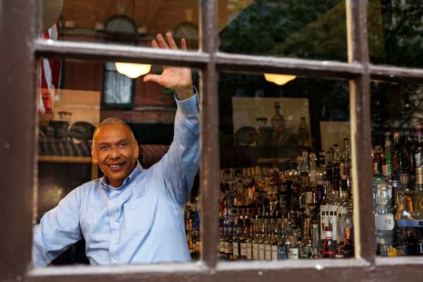 Smiling owner welcoming guests through the window at Serafini Italian fusion restaurant in historic downtown Frankfort, Kentucky.