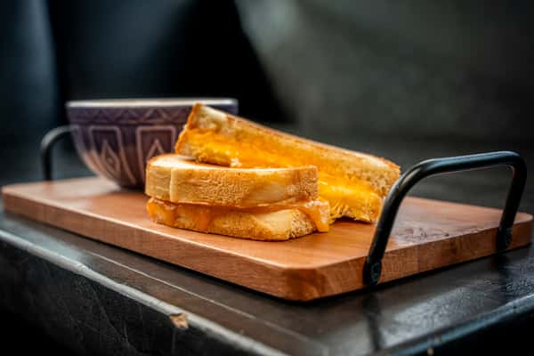grilled cheese on top of a wooden plate on a table