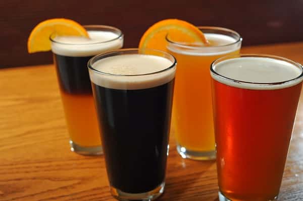Four beers on wooden bar with lemon wedge