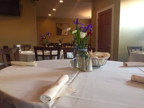 round tables and chairs in the dining room with table cloths and flowers
