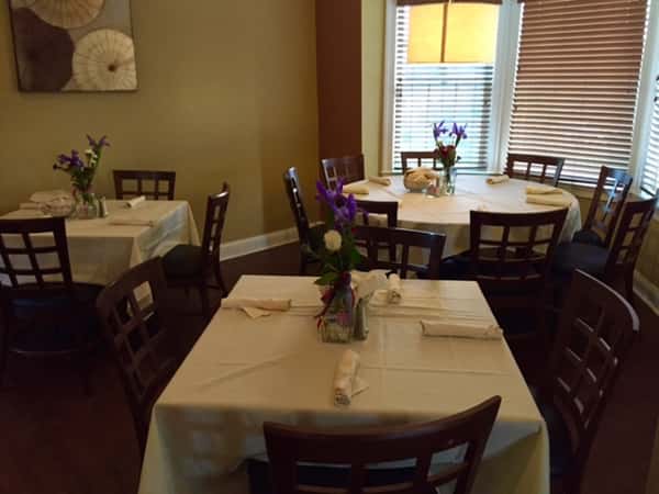 tables with table cloths and chairs with flowers