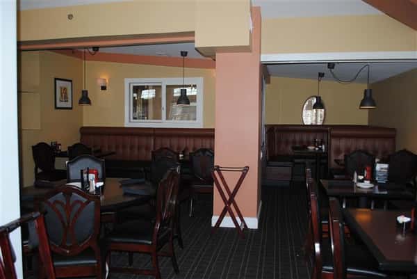 room filled with tables and chairs with two tv's