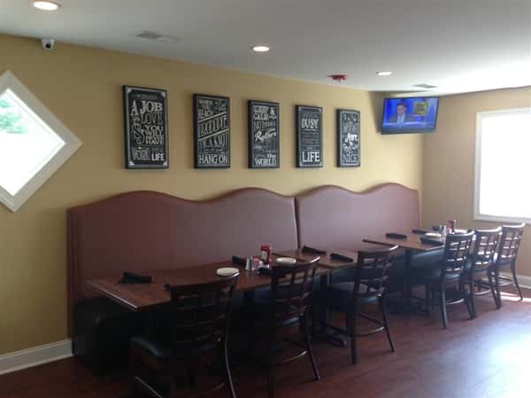 tables with half booth and half chairs with signs on the wall and tv in the corner