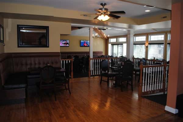 room filled with tables and chairs with two tv's