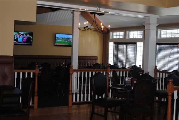 room filled with tables and chairs with two tv's