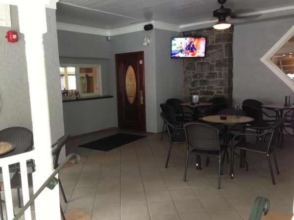 Rounded tables with chairs on a tile floor with a tv on the wall