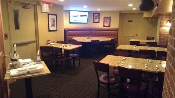 Set tables in the restaurant and a table with cleaning supplies and rolled silverwear