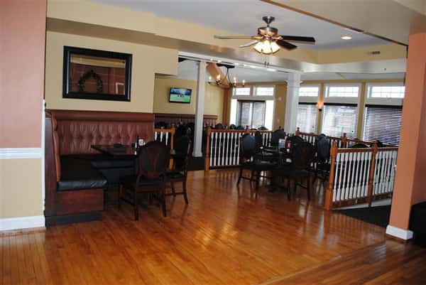 room filled with tables and chairs with two tv's on the wall