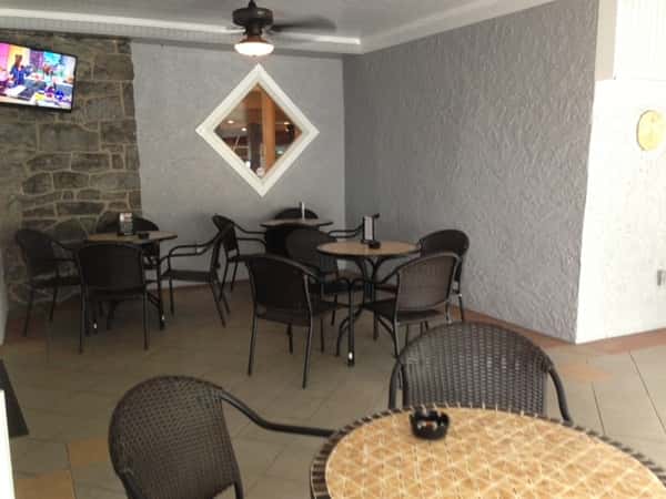 Rounded tables with chairs on a tile floor with a window in the wall