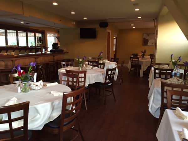 round tables and chairs in the dining room with table cloths and flowers