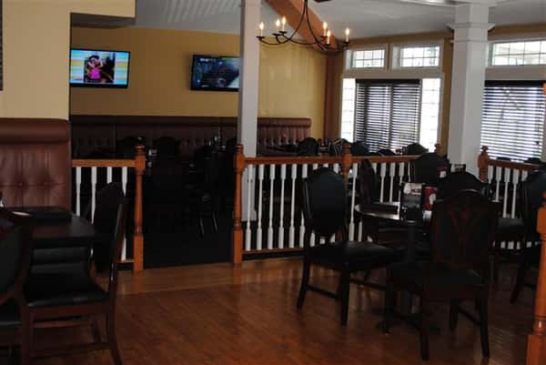 room filled with tables and chairs with two tv's