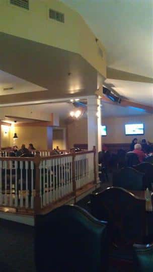 room filled with tables and chairs with two tv's on the wall