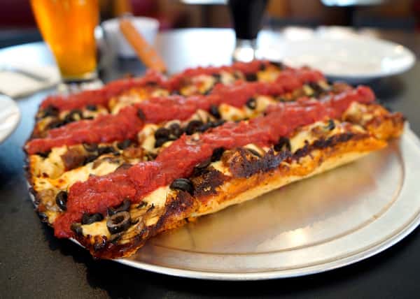thick crust square pizza with parinara sauce, cheese and black olives on a tray