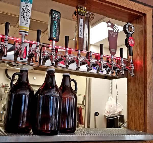 Three glass growlers under the beer taps