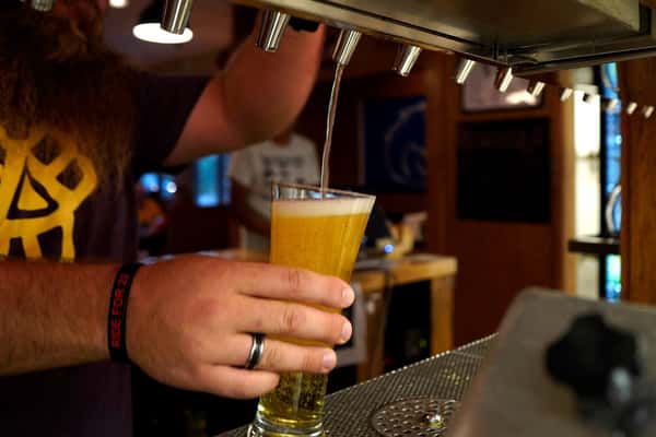bartender pouring a light beer from the tap into a glass.