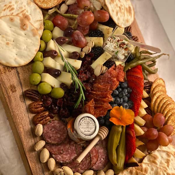 charcuterie board with assorted meats, cheeses, fruits, vegetables, crackers and nuts