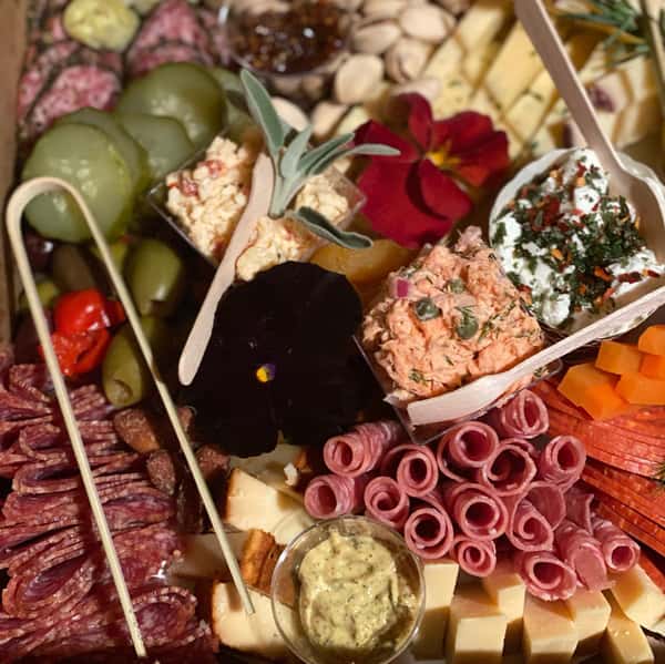 charcuterie board with assorted meats, cheeses, fruits, vegetables and nuts