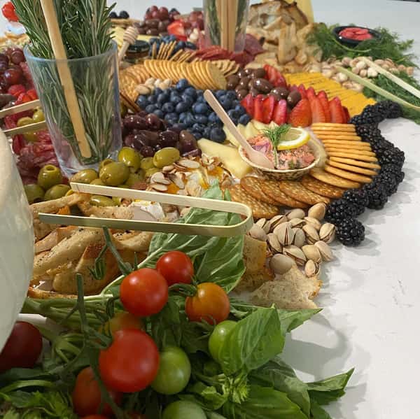 charcuterie board with assorted meats, cheeses, fruits, vegetables, crackers and nuts