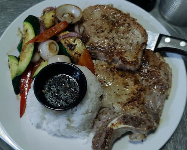 Grilled pork chops served with white rice, sautéed vegetables, and soy dipping sauce.