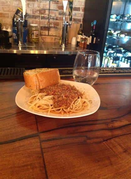 spaghetti on a plate with garlic bread and a glass of water