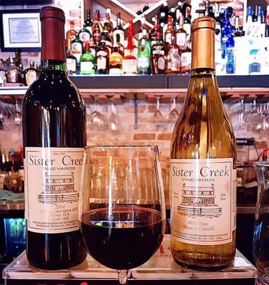 two bottles of wine and a glass of wine