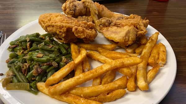 Plate of crispy fried chicken with golden fries and seasoned green beans served on a white diner plate.