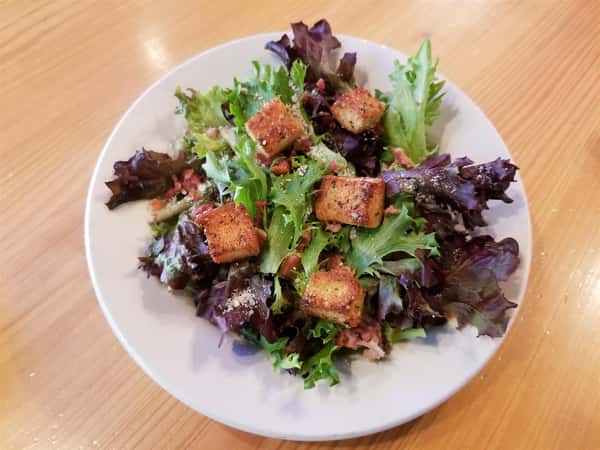 rustic Caesar salad is A unique blend of European small leaf lettuces, with the traditional toppings of Parmesan Cheese, Bacon Bits, and Homemade Croutons, make this Caesar Salad truly unique!