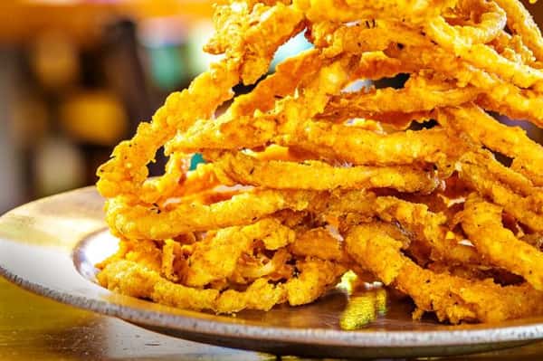 deep fried onion rings stacked together on a plate