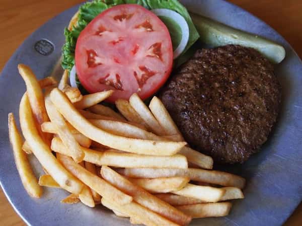 burger on a bun with tomatoes, lettuce and a side of fries