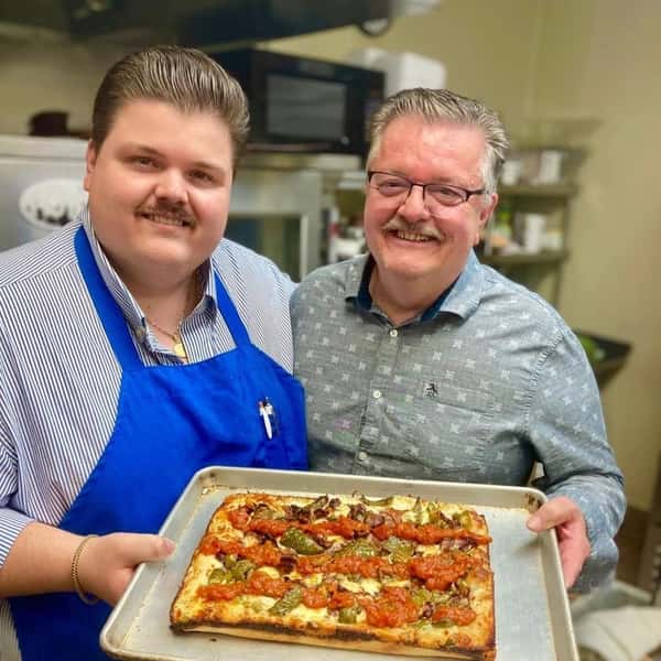 Two men holding a pizza pan
