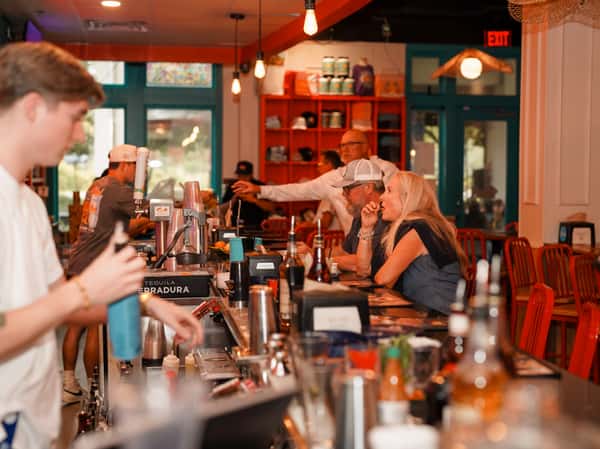 Bartender serving guests at a lively restaurant bar.