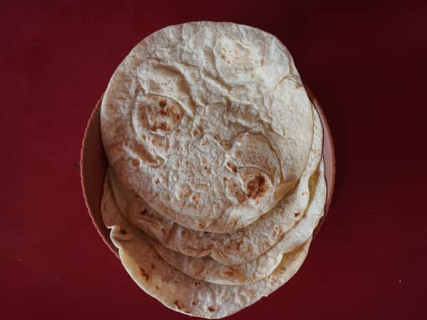 Stack of fresh flour tortillas served on a plate.