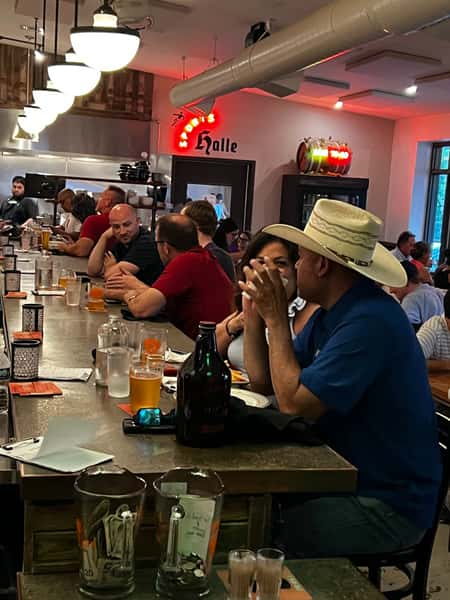 Lively evening crowd enjoying pints of craft beer and conversation at the indoor bar of Künstler Brewing in San Antonio.