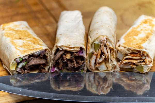 Four shawarma wraps with grilled beef and chicken fillings, sliced open to reveal onions, pickles, and seasonings.