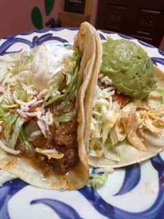 Two tacos from Joselito's catering taco & tostada bar in Los Angeles, served on soft corn tortillas with shredded beef, chicken, lettuce, sour cream, and guacamole.